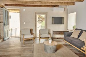 een woonkamer met een bank en stoelen en een tv bij Le Pas De Moineau in Lhuis