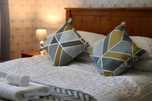 a bed with two pillows on top of it at EXQUISITE FOLK VICTORIAN ONE-BED HOUSE: in Leeds