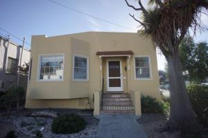 una casa amarilla con una puerta y una palmera en Peaceful home 20 min ferry ride to SF en Alameda