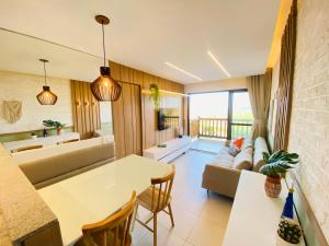 uma cozinha e sala de estar com uma mesa e um sofá em Apartamento luxo no VG SUN Cumbuco com vista para o mar em Cumbuco
