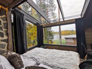 a bedroom with a bed and a large window at Glass Igloos by the water - Lasisviitit in Laukaa