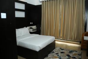 ein Schlafzimmer mit einem Bett und einem großen Fenster in der Unterkunft Hotel Capitol in Ikeja