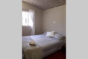 ein Schlafzimmer mit einem Bett mit Hut darauf in der Unterkunft Casa en El Manzano Histórico, Valle de Uco in Tunuyán