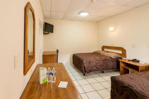 Cette chambre comprend 2 lits et une table. dans l'établissement Hotel Sntenario, à Chihuahua