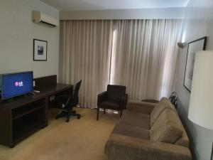 a living room with a couch and a desk with a computer at Bonaparte Hotel Flat Particular in Brasília