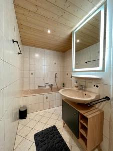 een badkamer met een wastafel, een spiegel en een bad bij Suite Home Mittenwald in Mittenwald