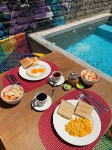 a table with plates of breakfast food next to a swimming pool at Imagine hostel in Santa Marta