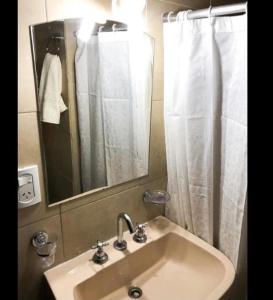 een wastafel in de badkamer met een spiegel en een douchegordijn bij Depto Temporario Entre Rios 729 in Salta