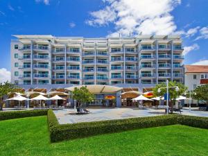 Un gran edificio blanco con sombrillas delante. en Waterfront Apartment 216, en The Entrance