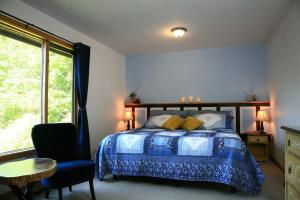 ein Schlafzimmer mit einem Bett, einem Stuhl und einem Fenster in der Unterkunft The Burgundy Dream Bed And Breakfast in Fall River