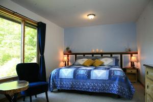 a bedroom with a bed and a chair and a window at The Burgundy Dream Bed And Breakfast in Fall River