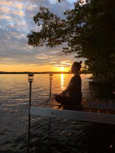 a woman sitting on a bench near a body of water at The Burgundy Dream Bed And Breakfast in Fall River