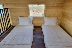 2 Betten in einem kleinen Zimmer mit Fenster in der Unterkunft 076 Tiny Home nr Grand Canyon South Rim Sleeps 8 in Valle