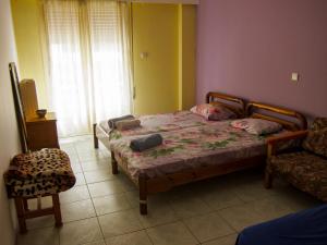 sypialnia z 2 łóżkami, krzesłem i oknem w obiekcie Antonio's Guest House w Atenach