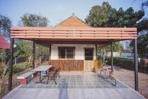 a pavilion with a picnic table and a house at Baansuanchan resort in Ban Tha Nam Tun