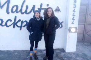 two women are standing in front of a sign at Maluti Backpackers in Phuthaditjhaba