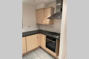 La cuisine est équipée de placards en bois et d'un four avec plaques de cuisson. dans l'établissement Luxurious & Cosy Apartment in Surrey, à Weybridge