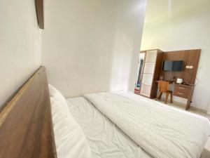 a large bed in a room with a desk at ANA INN Ambarawa Mitra RedDoorz in Semarang