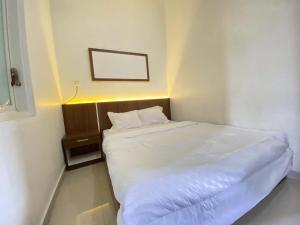a small bedroom with a white bed and a night stand at ANA INN Ambarawa Mitra RedDoorz in Semarang