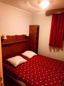 um pequeno quarto com uma cama com um cobertor vermelho em Appartement 6 pers. proche des pistes 71544 em Narreyroux