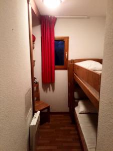 um pequeno quarto com uma cama e uma cortina vermelha em Appartement 6 pers. proche des pistes 71544 em Narreyroux