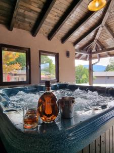 a bath tub with a bottle and two glasses in it at Хотелски комплекс САНЯ in Apriltsi