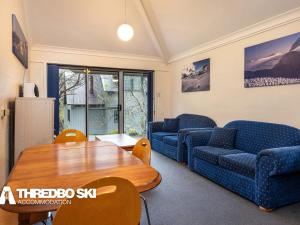 a living room with two blue couches and a table at Kirkwood 4 in Thredbo +3 photos