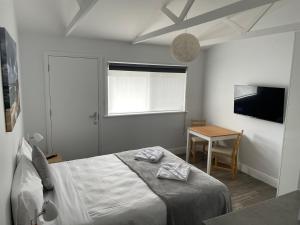 a bedroom with a bed and a table and a television at Robe Nampara Cottages in Robe