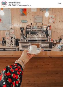 a person holding a cup and aucer in a coffee shop at Bnb Villa Lendi in Frattamaggiore