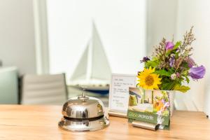 una mesa con una tetera y un jarrón de flores en Hotel Das kleine Glück - Adults Only en Sankt Peter-Ording
