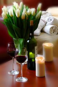 a table with two glasses of wine and a vase of flowers at Hotelik Amber REALIZUJEMY BON TURYSTYCZNY in Raszyn