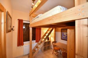 LʼHuezにあるAppartements Le Soleilの二段ベッド、デスク、はしごが備わるドミトリールームのベッド1台分です。
