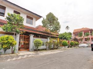 uma rua com uma casa branca com árvores e arbustos em OYO Life 90539 Taman Borobudur Guest House Syariah em Blimbing