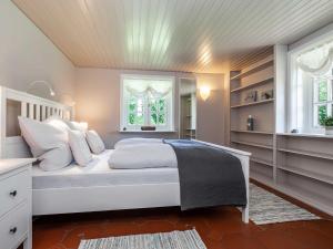 a bedroom with a white bed and two windows at Ferienhaus REETselig mit Pool Sauna in Klein Barkau