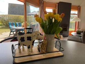 a table with a cow statue and a vase of flowers at Zeester 4 personen in Julianadorp