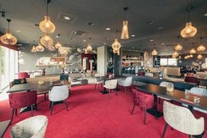 un restaurante con mesas y sillas sobre una alfombra roja en Monardo Hasenberg, en Widen