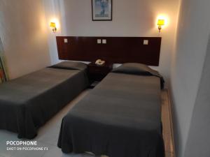 a hotel room with two beds and two nightstands at Hotel Alnacir in Faro