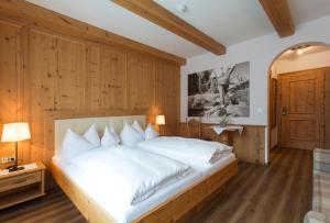 sypialnia z dużym białym łóżkiem i drewnianymi ścianami w obiekcie Hotel Englhof w mieście Zell am Ziller