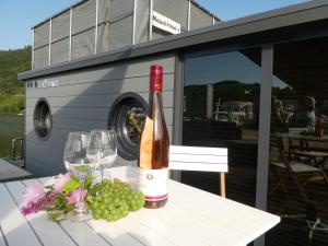 una botella de vino sentada en una mesa con copas de vino en Hausboot Moselrose in Pölich, en Detzem