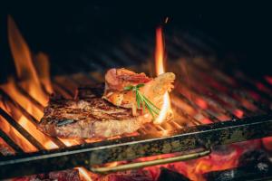 ein Stück Fleisch, das auf einem Grill mit Flammen kocht in der Unterkunft Monardo Hasenberg in Widen