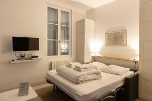 een slaapkamer met een bed met witte lakens en een televisie bij Résidence Quélin Honfleur in Honfleur