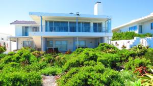 a house on the beach with bushes in front of it at On The Beach Apartments in Yzerfontein