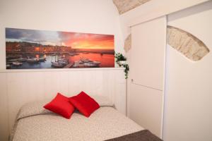 - une chambre avec un tableau au-dessus d'un lit et des oreillers rouges dans l'établissement Room 20 - Piccola Camera in pietra bianca, à Giovinazzo