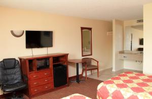 Habitación de hotel con TV, cama y escritorio. en Best Way Inn and Suites - New Orleans en Nueva Orleans