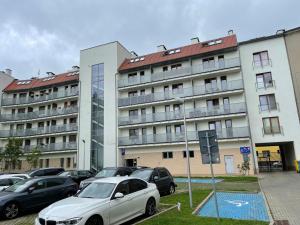 a parking lot with cars parked in front of a building at Sweet Apartment in Szczecin