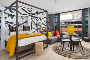 een slaapkamer met een bed, een tafel en een bank bij 16 on Bree Luxury Apartments in Kaapstad