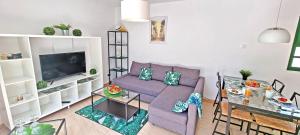 salon z fioletową kanapą i stołem w obiekcie Ferienwohnung PALM GARDEN - Costa Calma - Pool - GlasfaserInternet w mieście Costa Calma