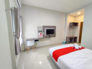 a white bedroom with a bed and a tv at RedDoorz Syariah near GOR Satria Area in Purwokerto