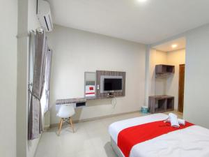 a white room with a bed and a tv at RedDoorz Syariah near GOR Satria Area in Purwokerto