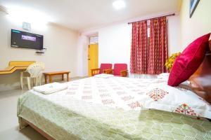 a bedroom with a bed with red chairs and a tv at Hotel TamilNadu - Madurai I in Madurai +10 photos